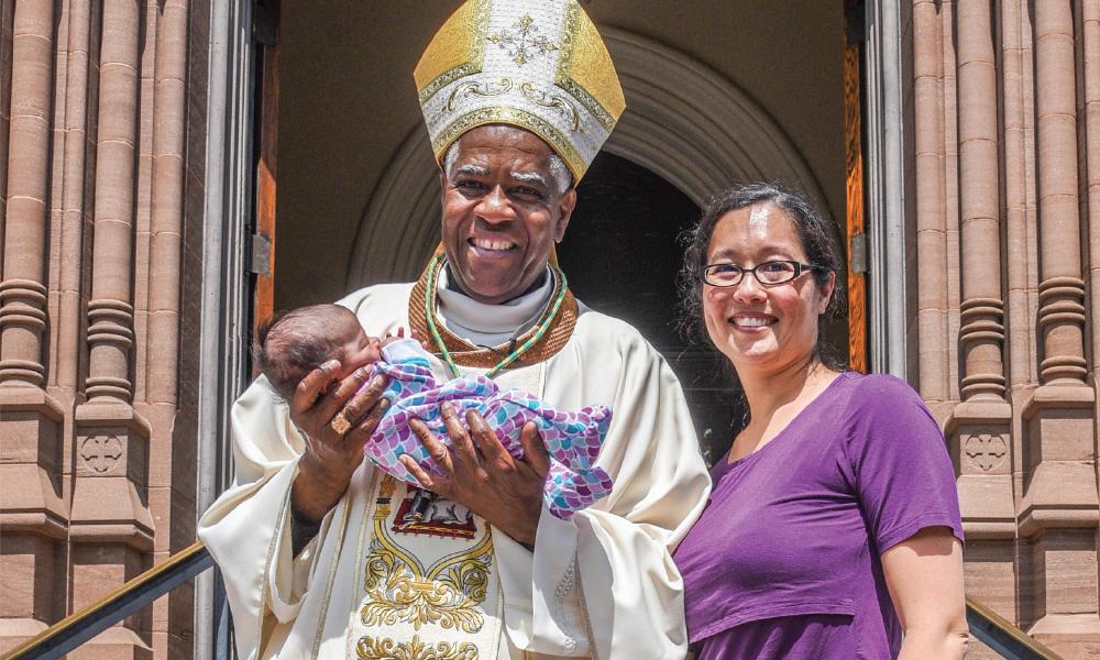 Bishop Jacques Fabre-Jeune with parishioner, holding baby