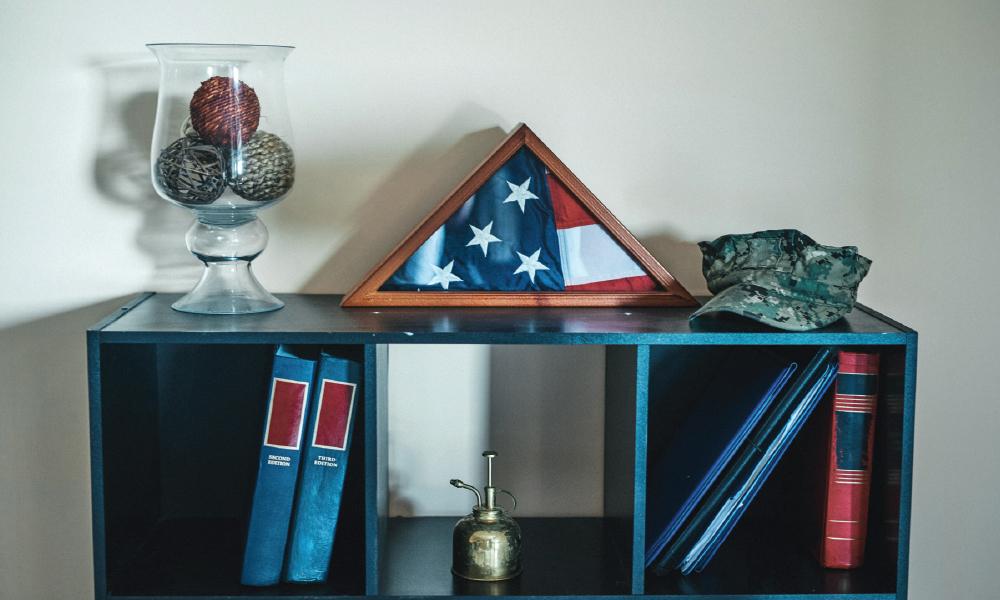 Bookshelf featuring a folded American flag and soldier's cap
