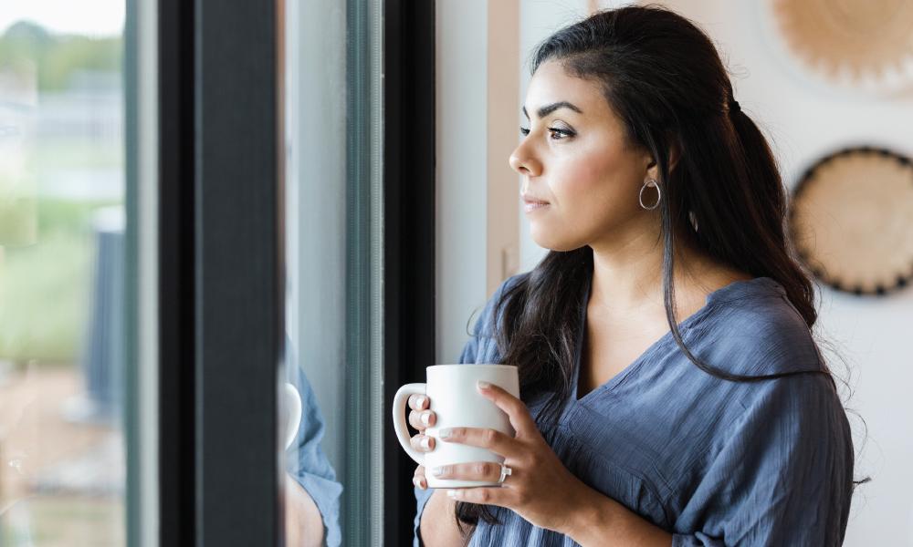 Woman holding coffee mug and looking out a window