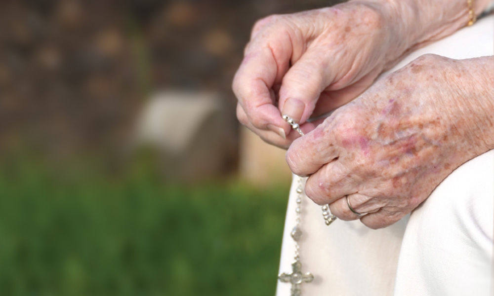 Elderly hands holding a rosary