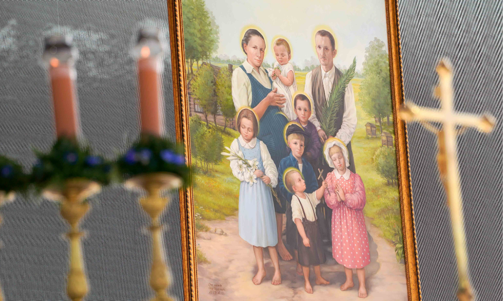 A portrait of Józef and Wiktoria Ulma, who is pregnant, and their six children hangs near the altar during their beatification Mass Sept. 10, 2023, in Markowa, Poland. Pope Francis prayed the family, killed for hiding Jews during World War II, would be an example to all Christians of goodness and service to those in need. (CNS photo/Justyna Galant)