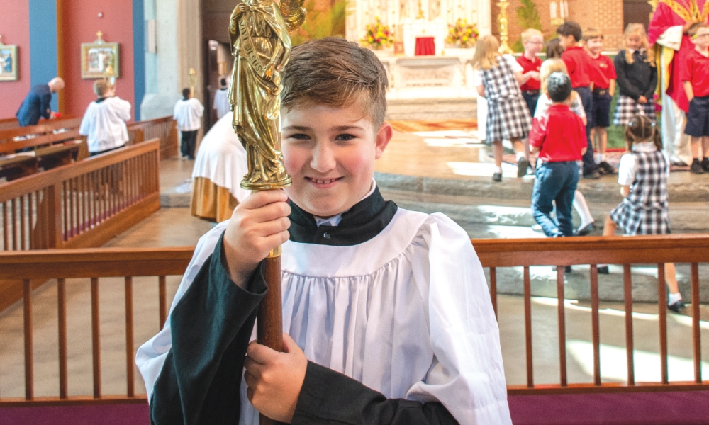 Altar server carrying the cross and smiling