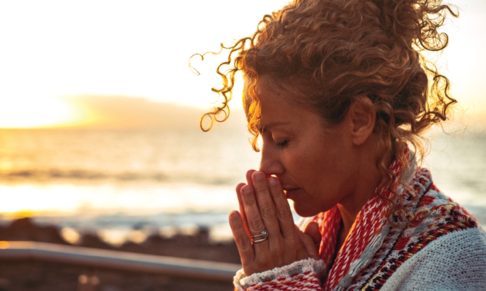 Woman praying with eyes closed and head bent down