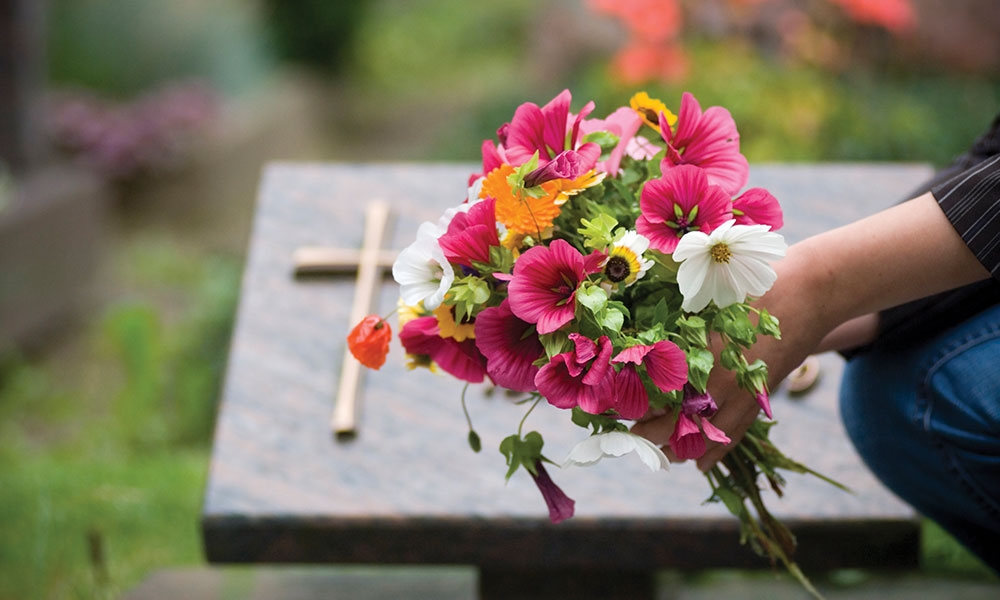 Person with flowers near gravesite