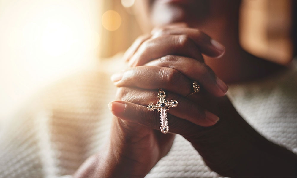 Woman praying with silver cross in her hands