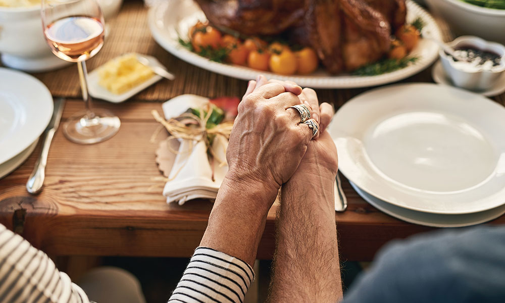 Hands held in prayer above dinner table