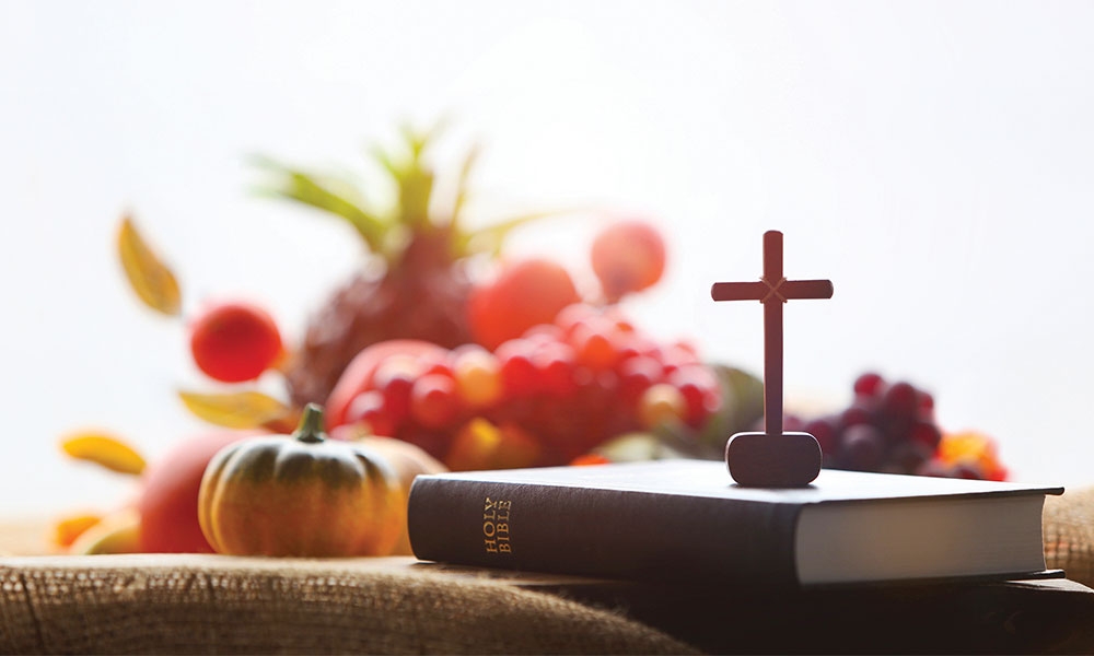 Bible and cross in front of a pile of fall fruits and vegetables