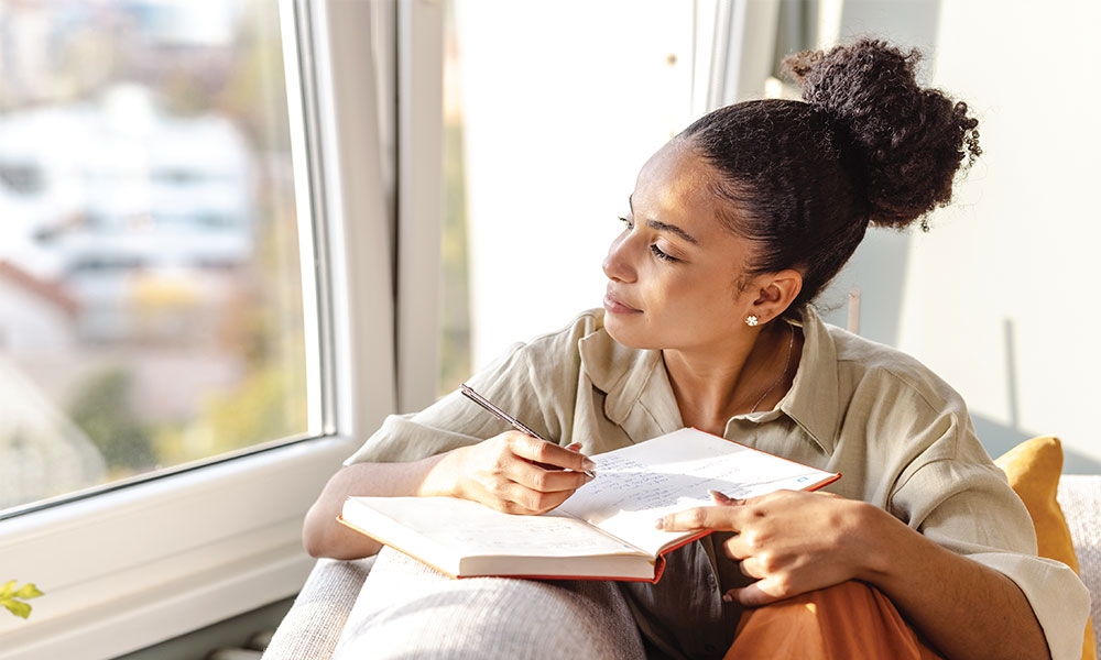 Woman journaling beside sunny window