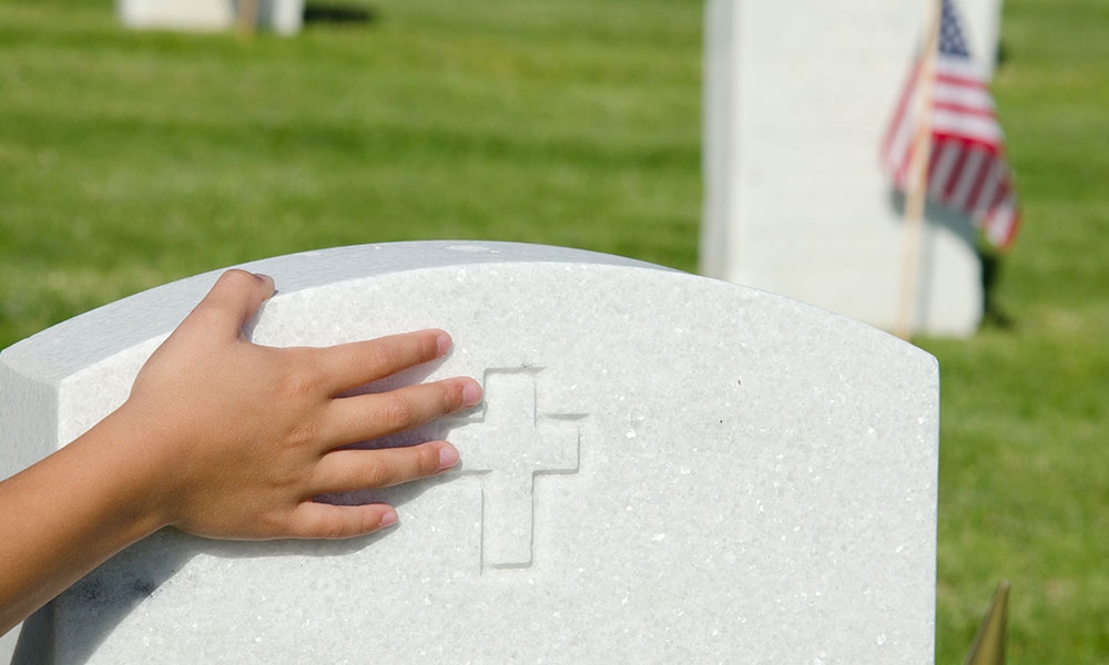 Child's hand on a soldier's headstone