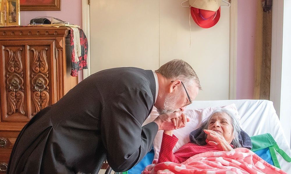 Father Richard C. Wilson, Aiken Dean, greets a homebound parishioner in March.
