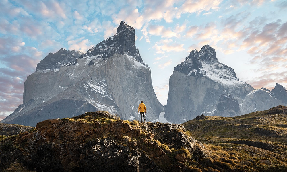 Image of a man standing in a valley, looking up at mountains