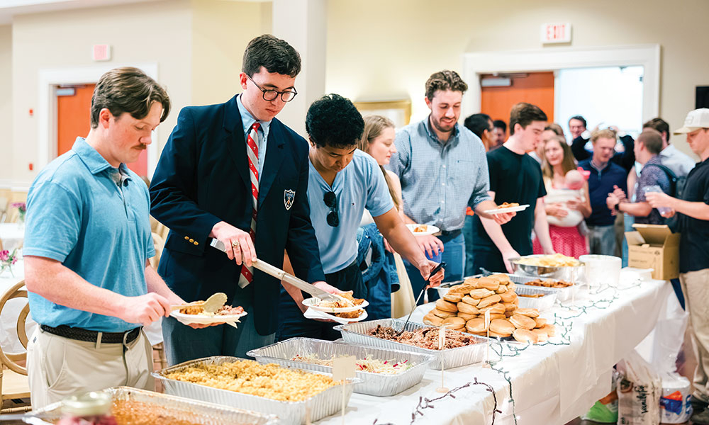 Young adults at a gathering serving themselves food