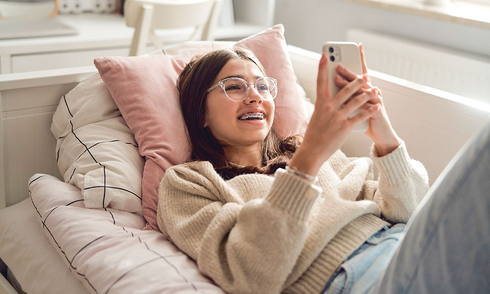 Teen girl laying on bed on her phone