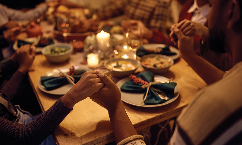 People around a table, holding hands and praying