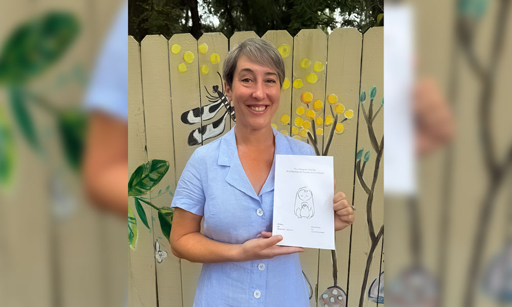 Suzanne Quinson holding a copy of her book The Penguin Family: A Collection of Stories for Children